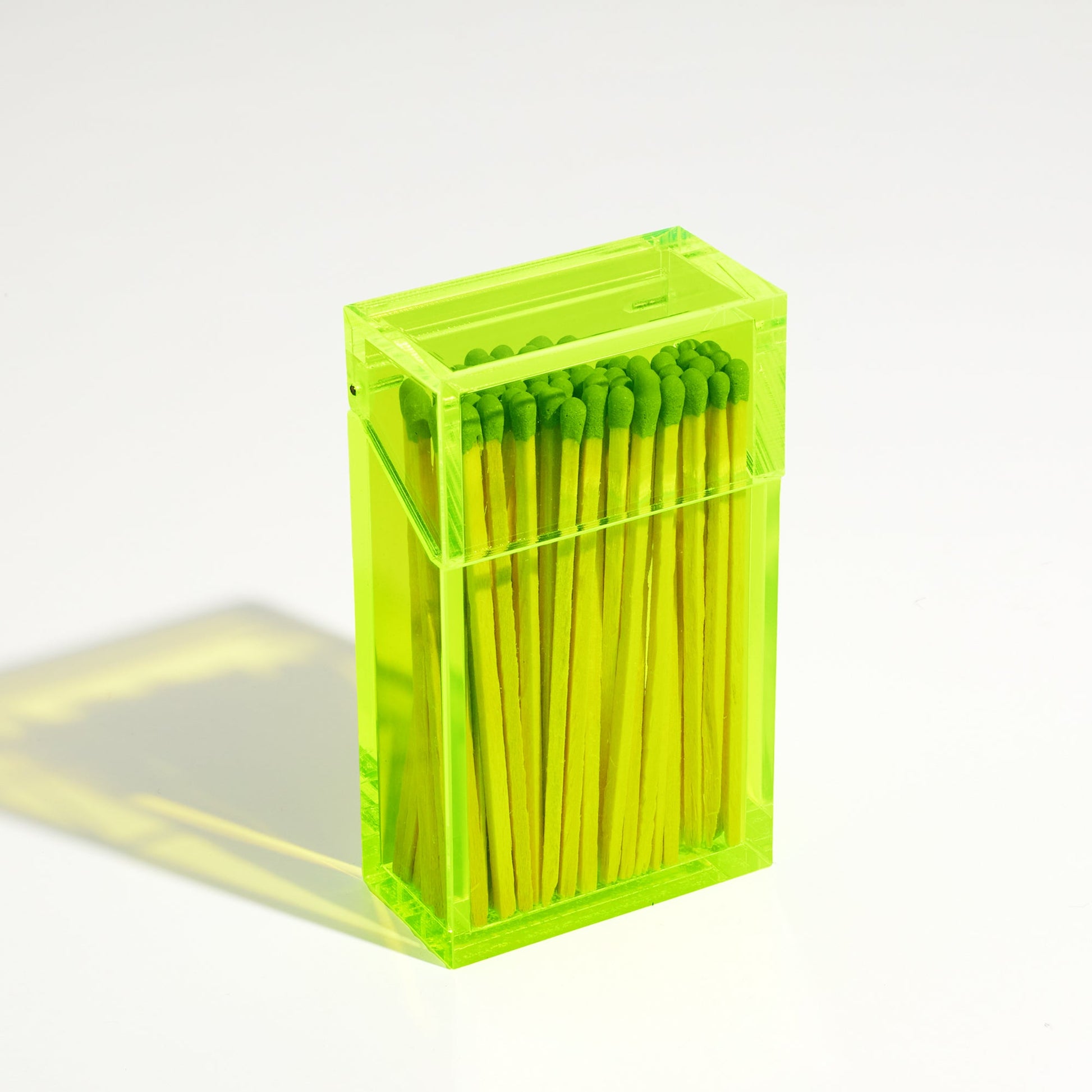 Closed Match holder shaped like a Cigarette Case. Made with neon green acrylic. Case holds Black matches in it.