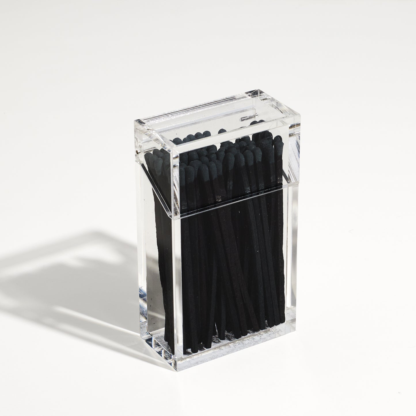 Closed Match holder shaped like a Cigarette style acrylic case with black matches in it.