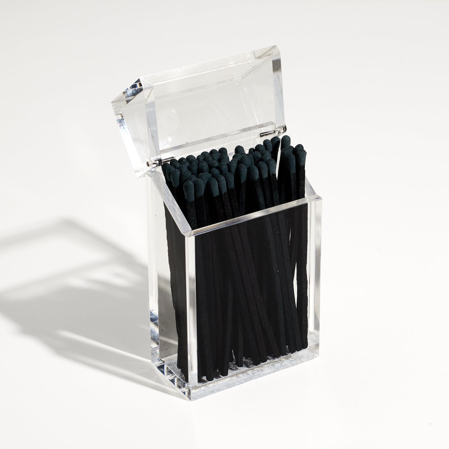Match holder shaped like a Cigarette style acrylic case with black matches in it.