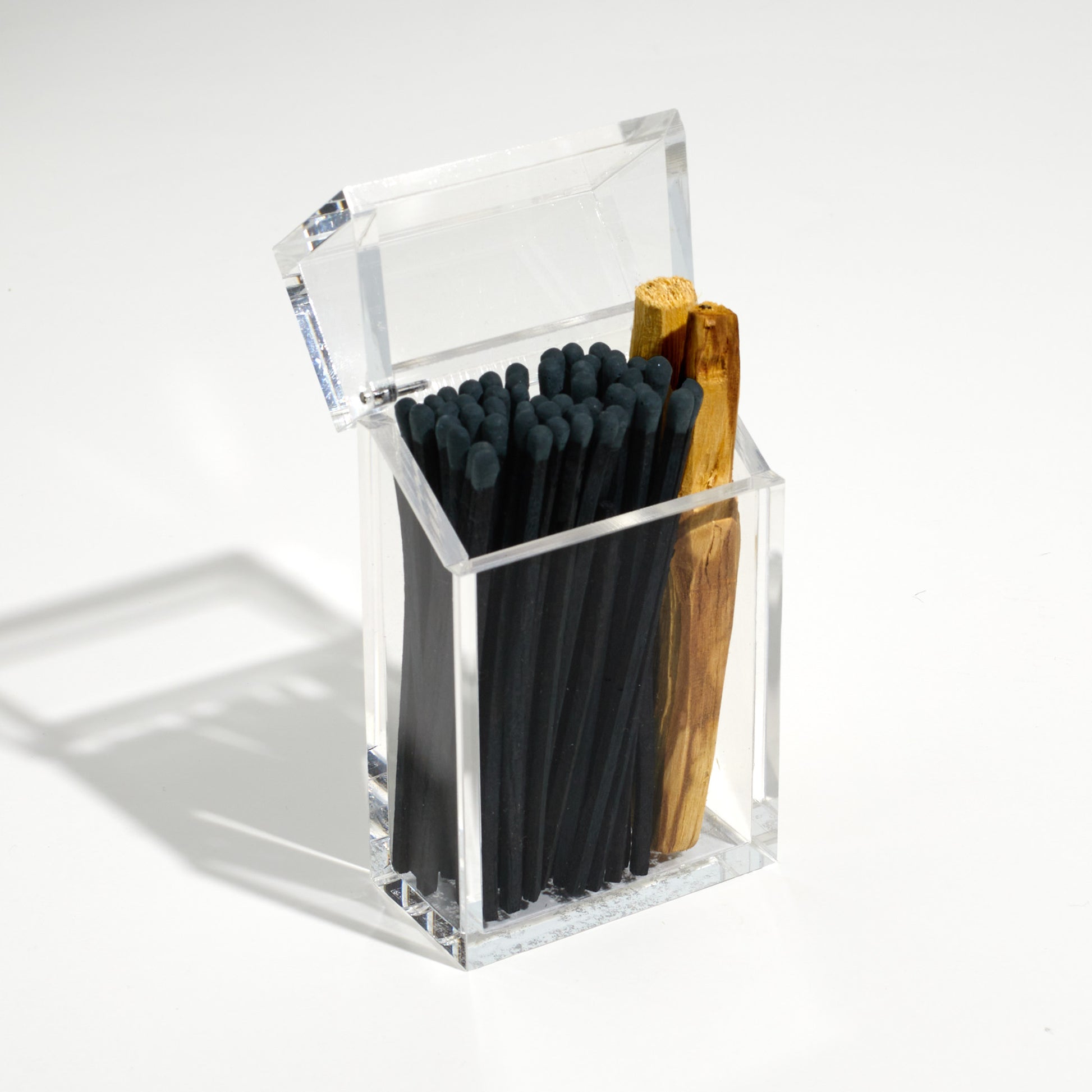 Opened Cigarette style acrylic case with Black matches and palo santo in it. 