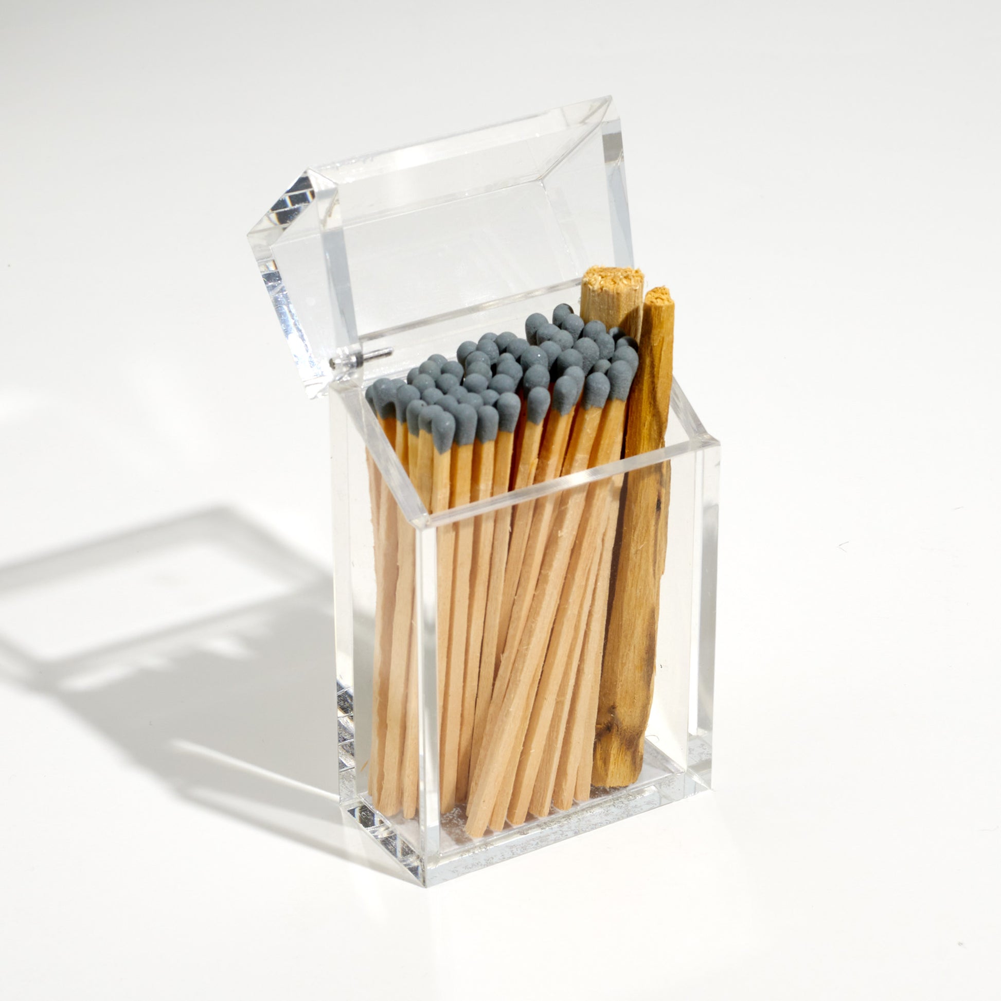 Opened Cigarette style acrylic case with gray matches and palo santo in it. 