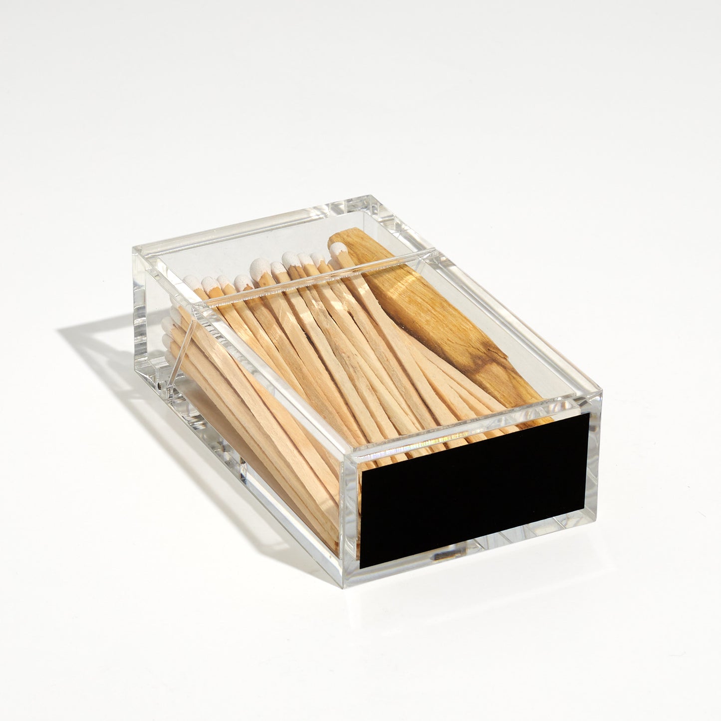 Cigarette style acrylic case with white matches and palo santo in it laid down to feature the striker sticker at the bottom of the case. 